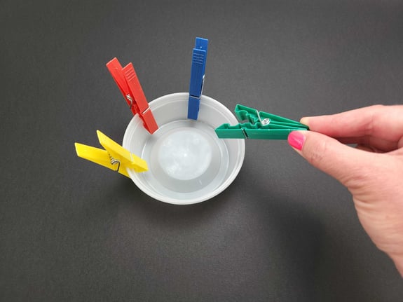 Person pinching colored clothespins to improve fine motor control