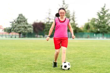 young woman kicking soccer ball in a field