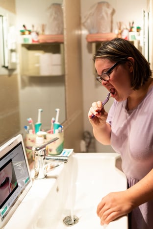 Young woman with Down Syndrome brushes teeth using MapHabit.