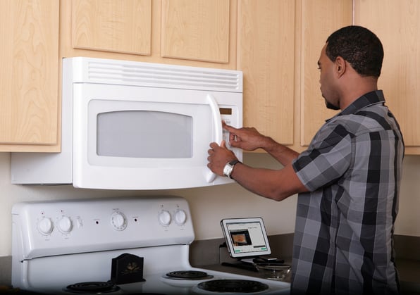 black man using a visual support to use the microwave