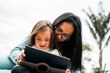 mother and daughter with Down syndrome with tablet outdoors