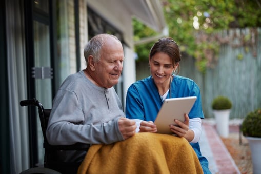 man in wheelchair with home health aide using tablet
